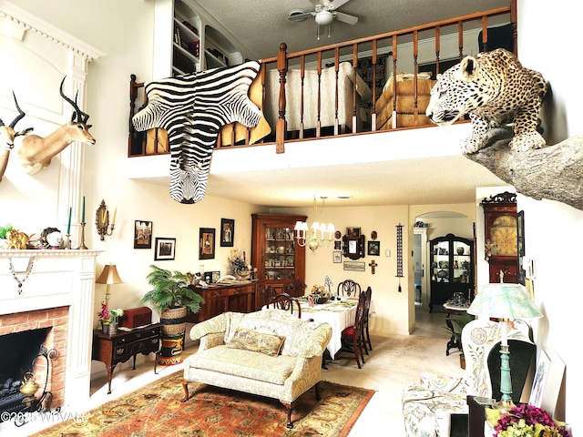 living area with a ceiling fan, a fireplace, arched walkways, and a towering ceiling