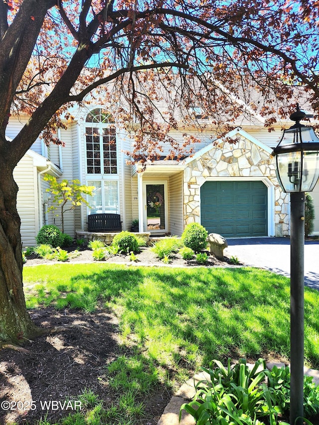 view of front of property with a garage, asphalt driveway, and stone siding