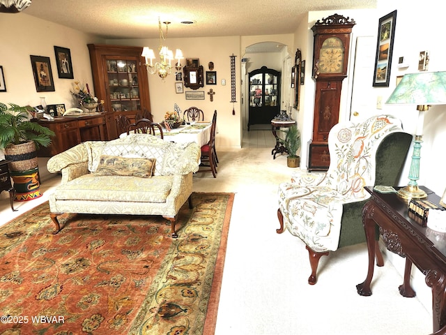 living room featuring arched walkways, a chandelier, a textured ceiling, and light carpet