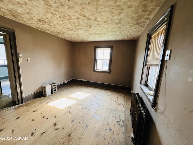 spare room with hardwood / wood-style floors and radiator heating unit