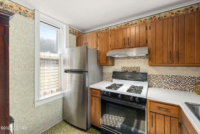 kitchen with tasteful backsplash, sink, stainless steel refrigerator, and gas range