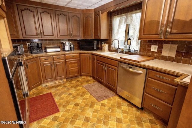 kitchen featuring backsplash, tile countertops, dishwasher, and sink