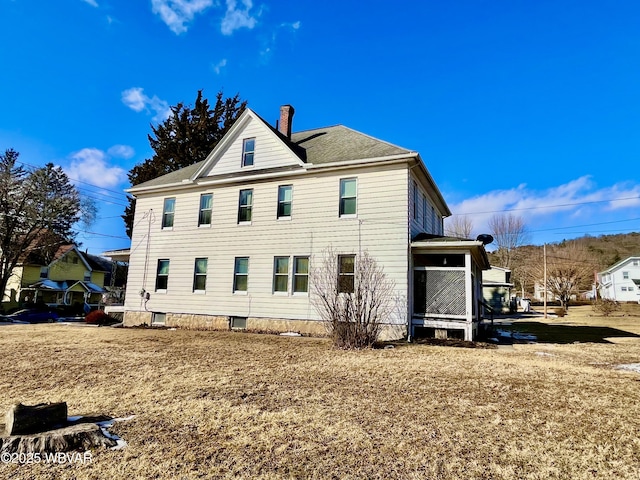 rear view of house with a chimney and a lawn