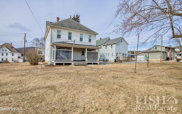 back of property with a chimney, a porch, and a lawn