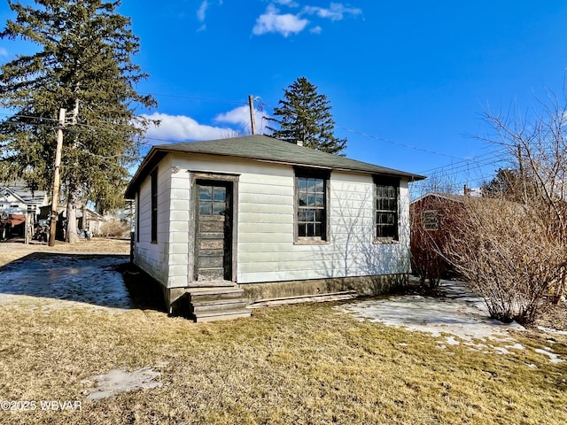 back of property with entry steps and a yard