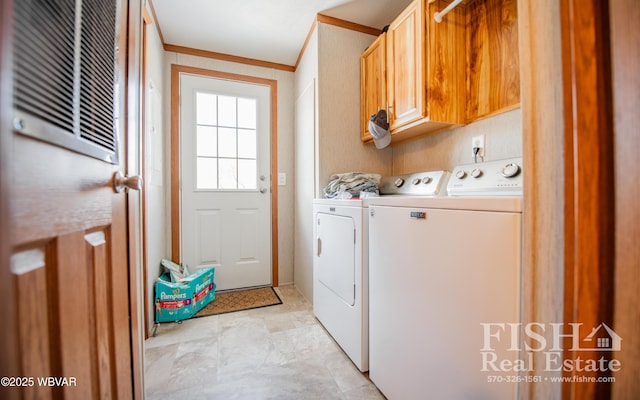 laundry area featuring washing machine and dryer, cabinets, and ornamental molding