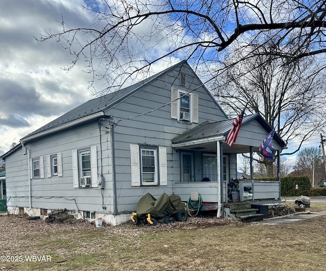 view of side of home featuring covered porch and a yard