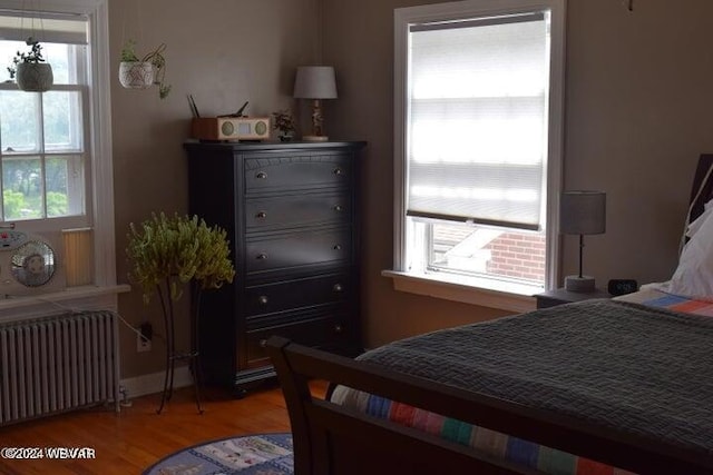 bedroom featuring radiator heating unit, multiple windows, and hardwood / wood-style floors