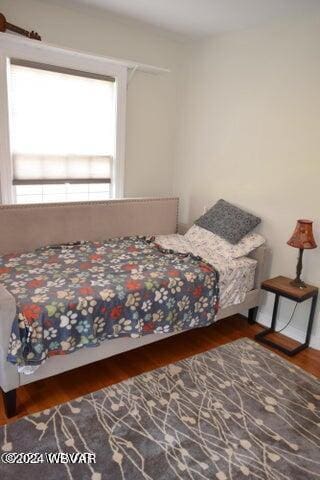 bedroom with multiple windows and dark wood-type flooring