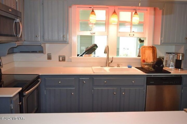 kitchen featuring appliances with stainless steel finishes, gray cabinetry, pendant lighting, and sink