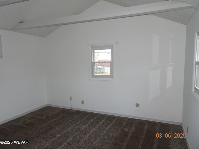 empty room with baseboards, vaulted ceiling, and dark colored carpet