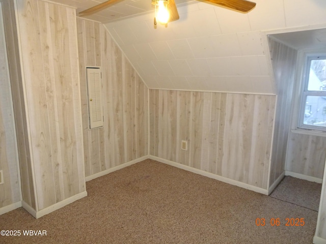 additional living space with vaulted ceiling, wood walls, and carpet flooring