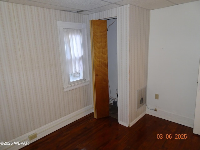 unfurnished bedroom with baseboards, wood finished floors, visible vents, and wallpapered walls