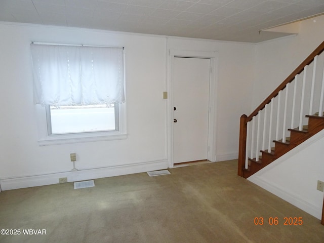 carpeted foyer entrance featuring stairway, baseboards, and visible vents