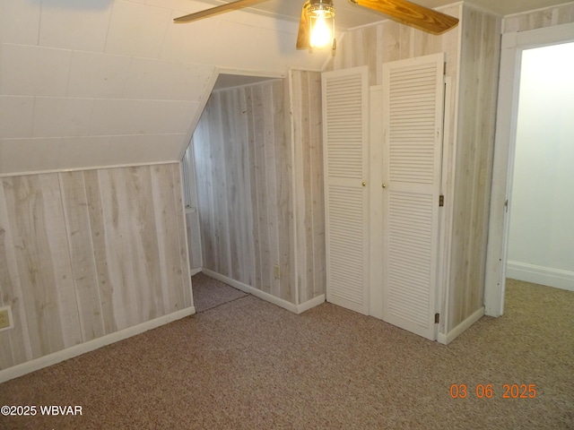 additional living space with lofted ceiling, carpet floors, wood walls, and ceiling fan