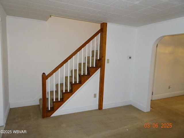 staircase with carpet floors, arched walkways, ornamental molding, and baseboards