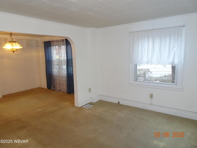 empty room with arched walkways, carpet flooring, and visible vents