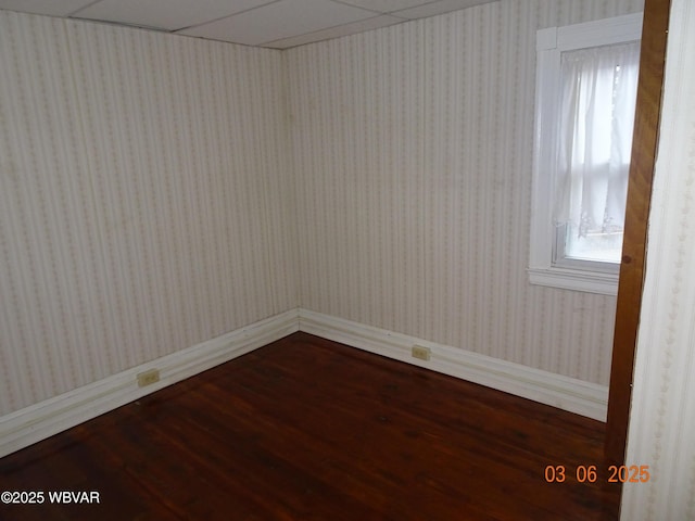 empty room featuring wood finished floors and wallpapered walls