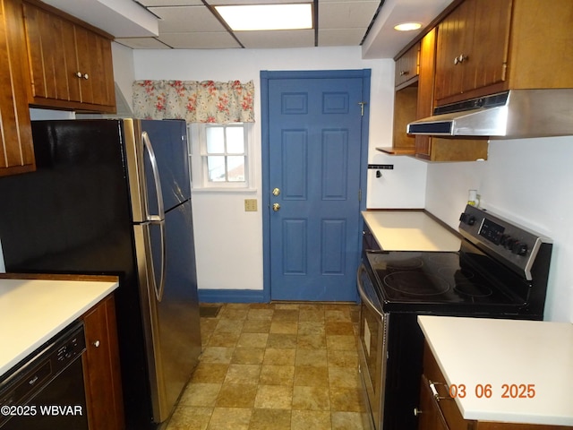 kitchen featuring light countertops, appliances with stainless steel finishes, brown cabinetry, a drop ceiling, and under cabinet range hood