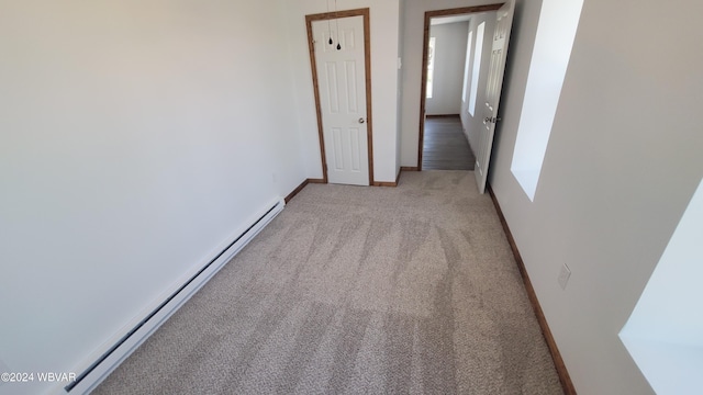 carpeted empty room with a baseboard heating unit