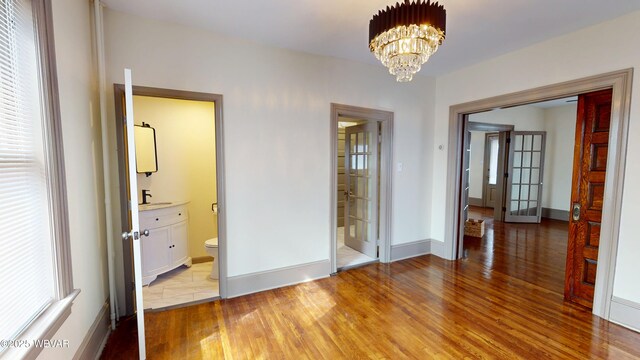 665 5th Ave, Williamsport, PA 17701 - unfurnished bedroom with a chandelier, light wood-style flooring, baseboards, and a sink