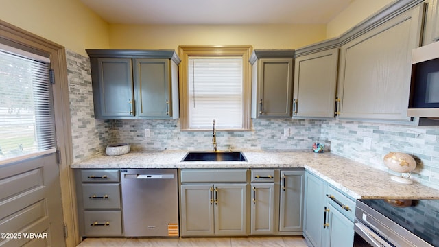 665 5th Ave, Williamsport, PA 17701 - kitchen featuring stainless steel dishwasher, a sink, light stone counters, and decorative backsplash