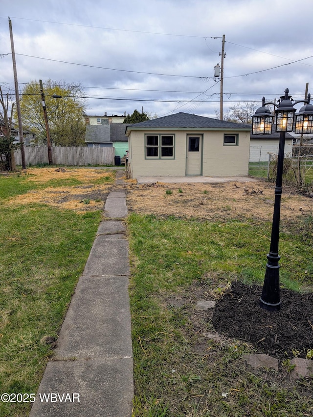 665 5th Ave, Williamsport, PA 17701 - view of front facade featuring an outbuilding, concrete block siding, a front yard, fence, and a shingled roof