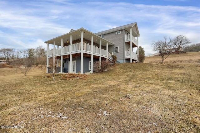 rear view of property featuring a balcony and a lawn