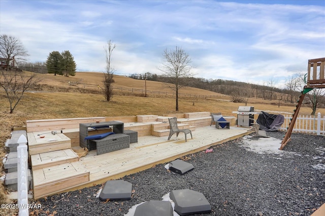 view of yard with a rural view, a wooden deck, and a fire pit