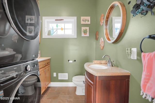 bathroom with vanity, toilet, and stacked washer / drying machine