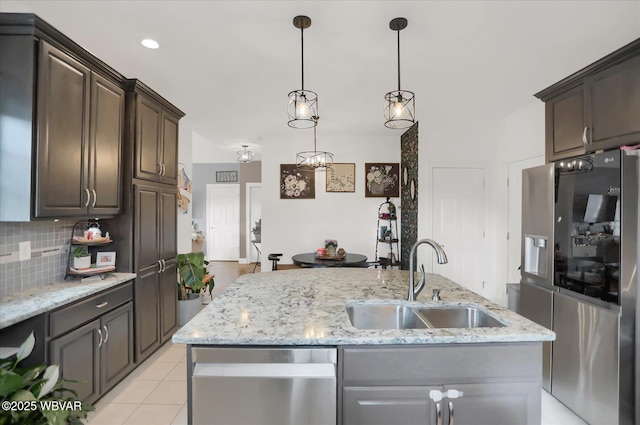 kitchen featuring dark brown cabinetry, sink, stainless steel appliances, and an island with sink