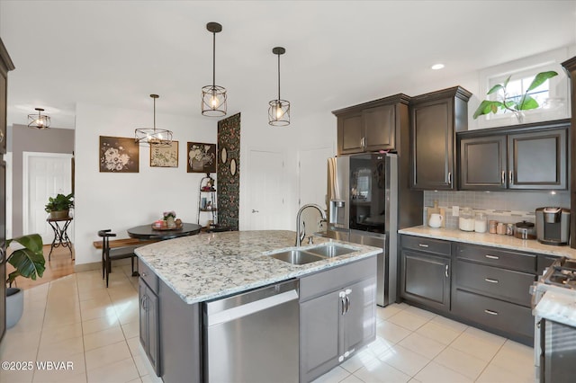 kitchen with sink, pendant lighting, stainless steel appliances, an island with sink, and tasteful backsplash