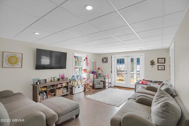 living room with french doors, concrete floors, and a drop ceiling