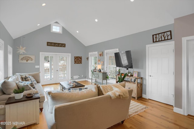 living room featuring high vaulted ceiling, light wood-type flooring, and french doors