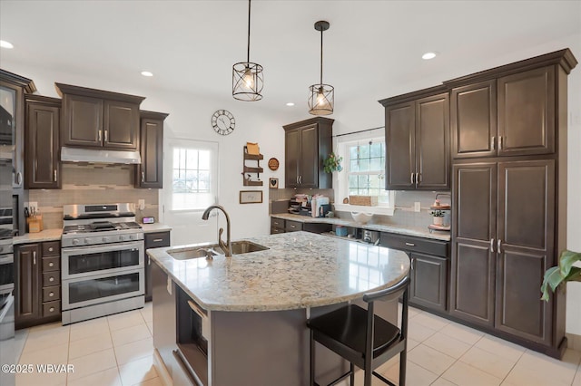 kitchen with sink, an island with sink, range with two ovens, and a healthy amount of sunlight