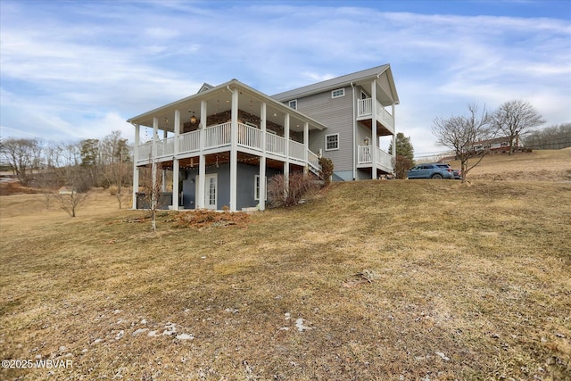 rear view of house featuring a lawn and a balcony