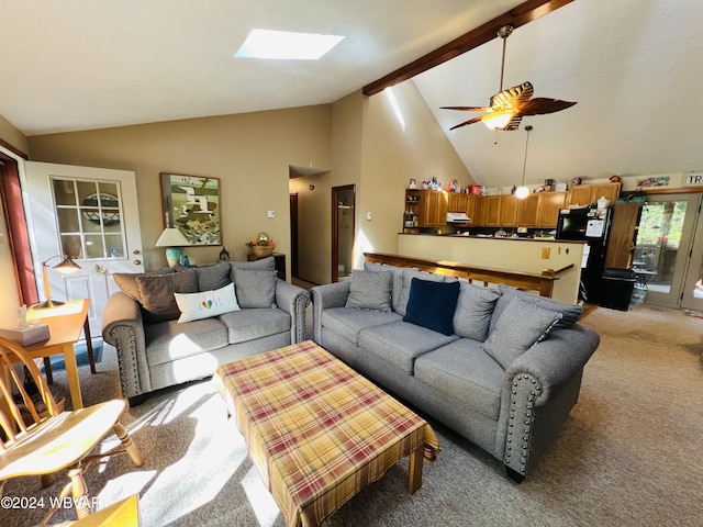 living room featuring light carpet, high vaulted ceiling, a skylight, ceiling fan, and beamed ceiling