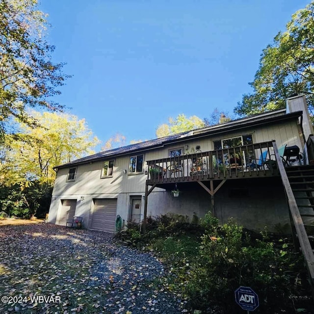 back of property featuring a garage and a deck