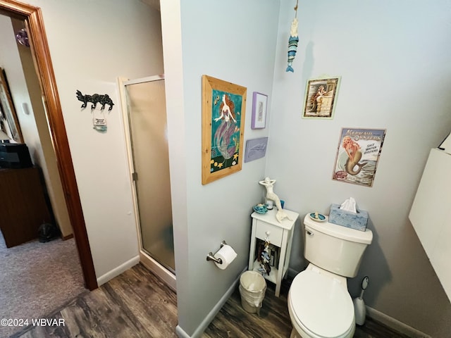 bathroom with hardwood / wood-style flooring, toilet, and a shower with shower door