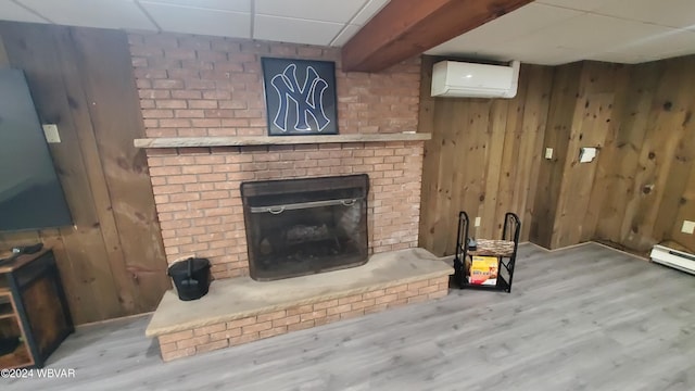 unfurnished living room featuring hardwood / wood-style flooring, a brick fireplace, a wall mounted AC, and wooden walls