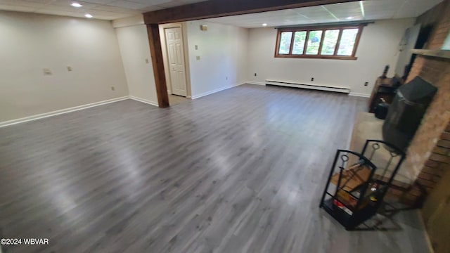 basement with dark hardwood / wood-style flooring, a baseboard radiator, and a paneled ceiling