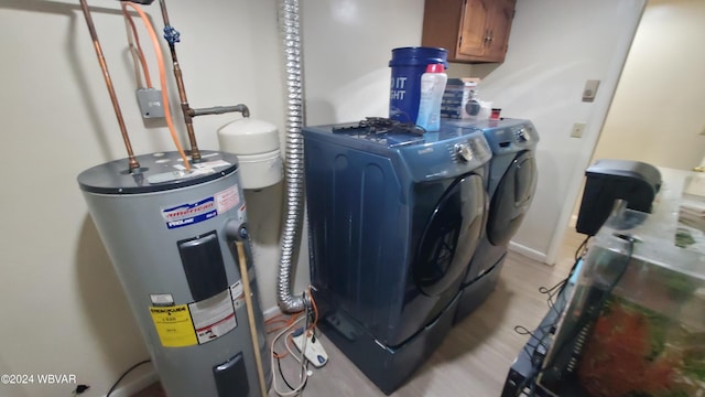 laundry room with water heater, washing machine and clothes dryer, and cabinets