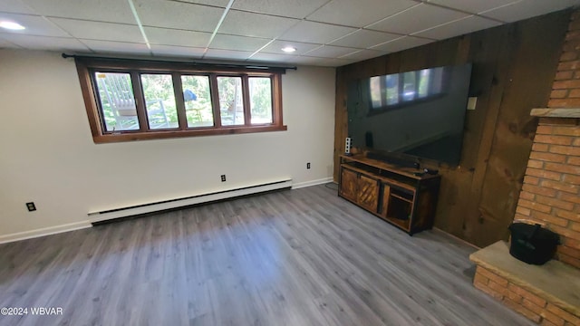 unfurnished living room featuring hardwood / wood-style flooring, a baseboard heating unit, and a drop ceiling