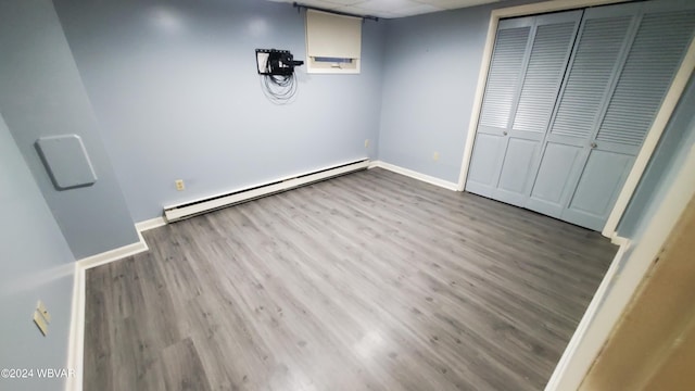 unfurnished bedroom with a baseboard radiator, a drop ceiling, light hardwood / wood-style floors, and a closet