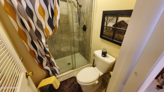 bathroom featuring a shower with door and toilet