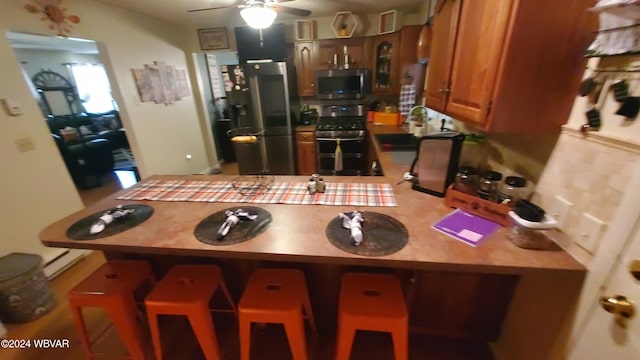 kitchen with sink, appliances with stainless steel finishes, a kitchen breakfast bar, kitchen peninsula, and ceiling fan