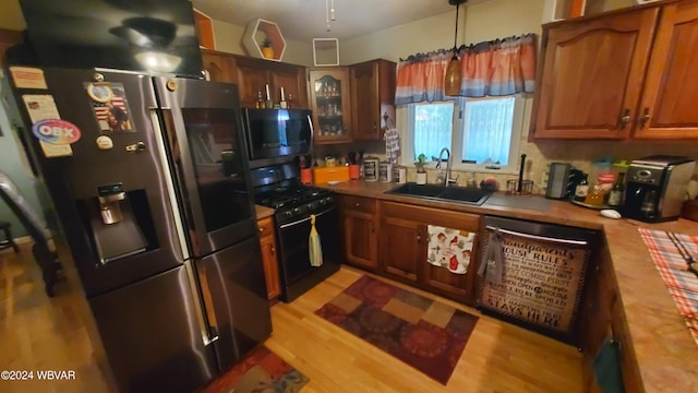 kitchen featuring stainless steel appliances, sink, pendant lighting, and light wood-type flooring