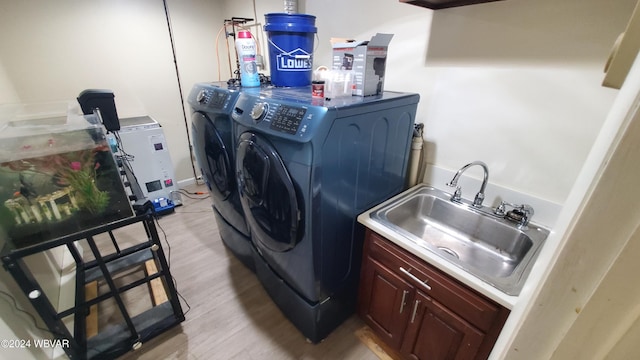 washroom featuring cabinets, separate washer and dryer, sink, and light hardwood / wood-style floors