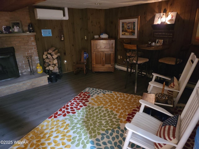 living room featuring wood walls, a paneled ceiling, a wall mounted air conditioner, a brick fireplace, and dark hardwood / wood-style floors