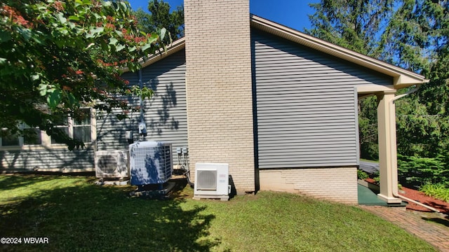 view of side of home with ac unit, a lawn, and central air condition unit